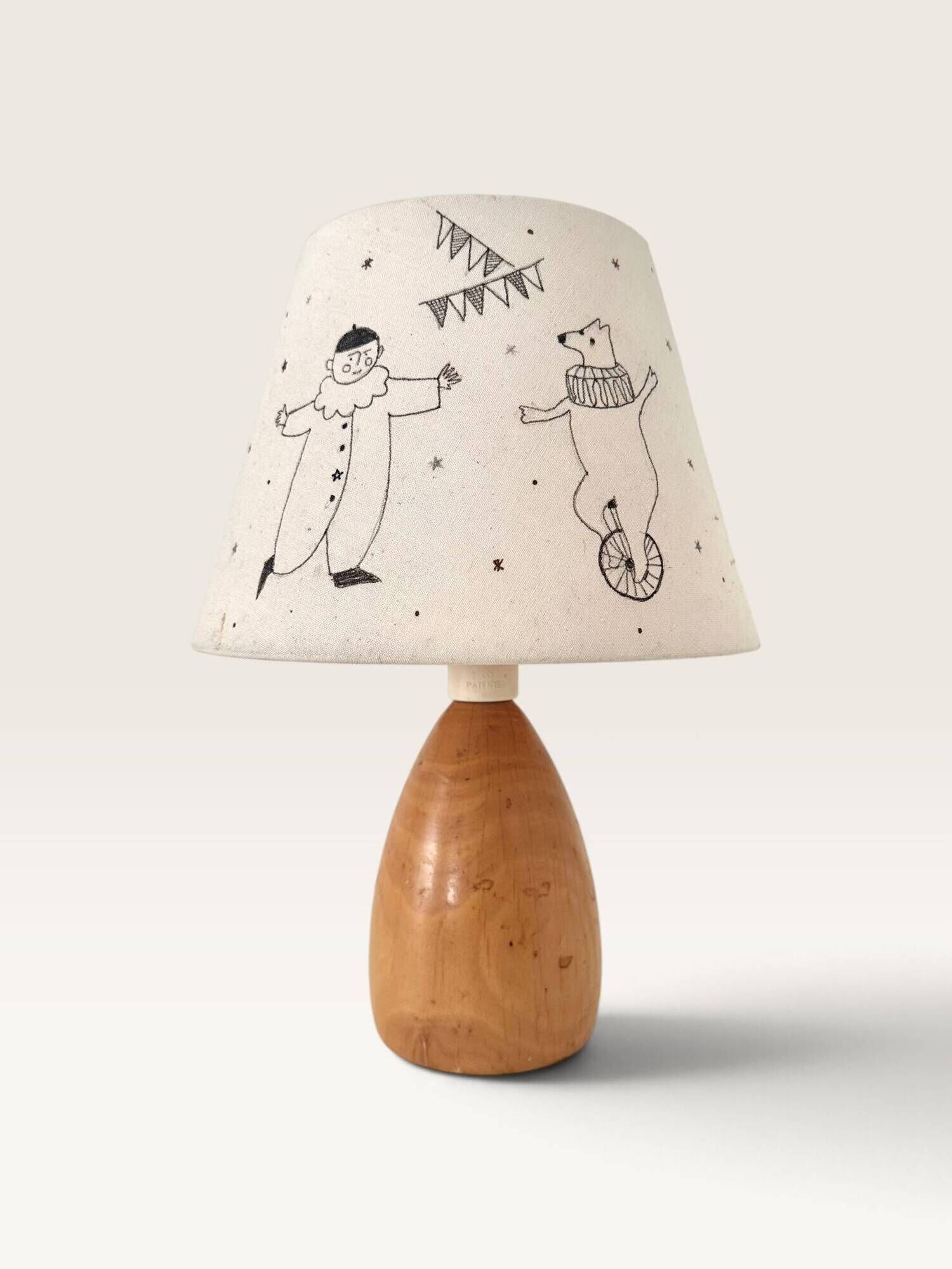 Wood-turned lamp with a hand-drawn lampshade, circus patterns.