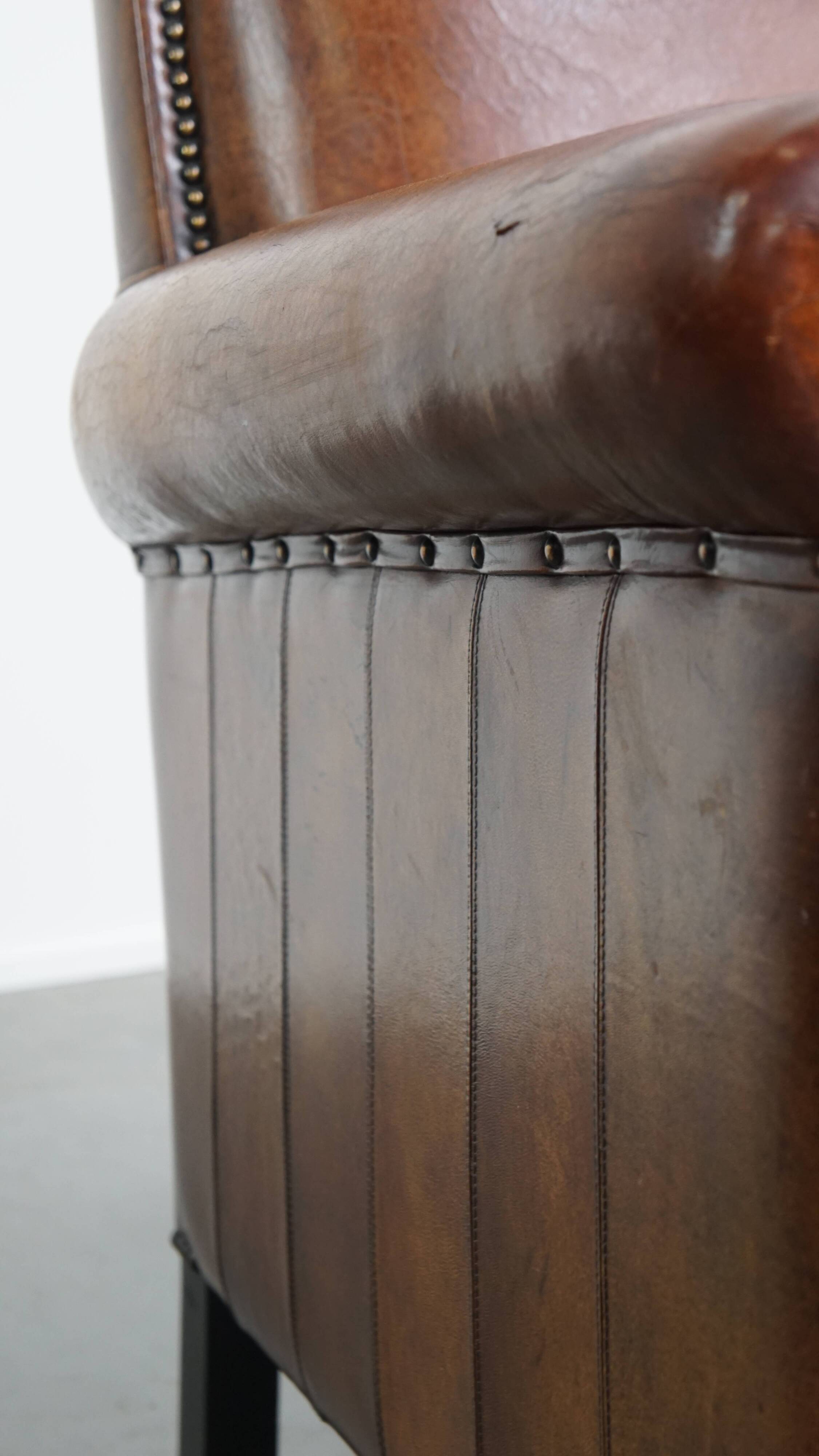 Sheepskin leather armchair in a cognac color with black piping