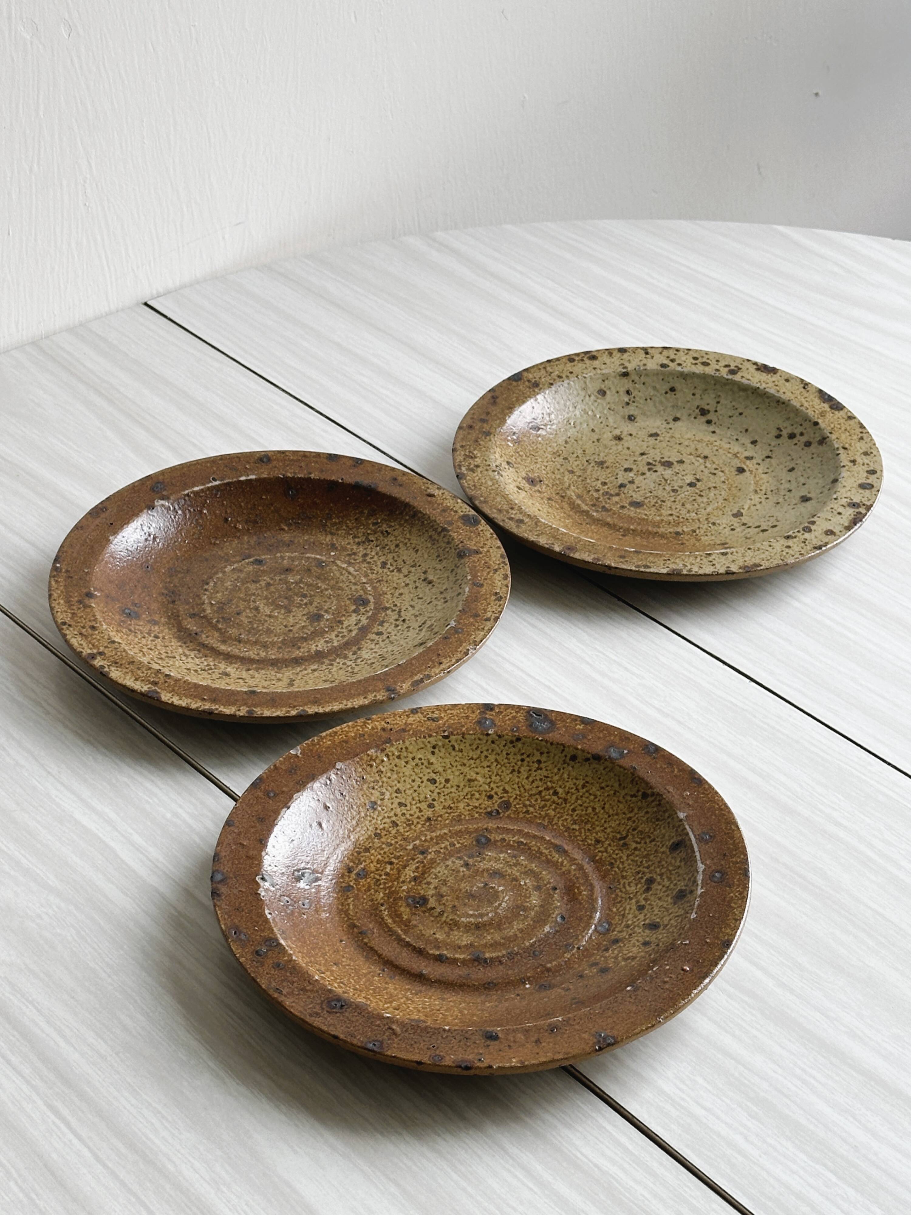 3 assiettes en grès rustique, finition mouchetée marron et beige.