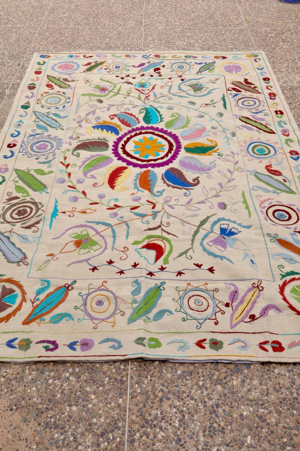 White suzani kilim rug with embroidered multi-colored patterns