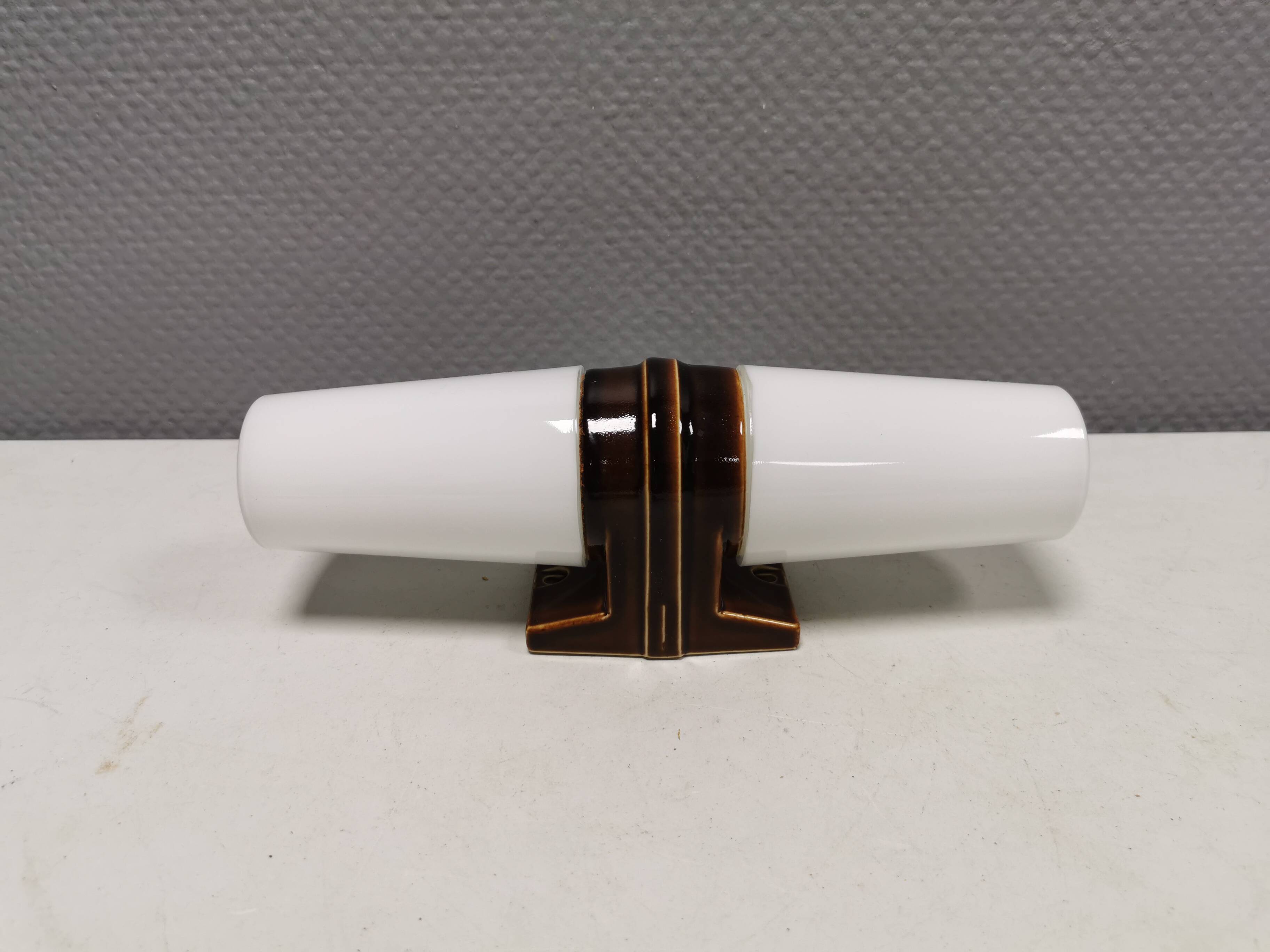 Old bathroom lamp with brown/golden ceramic base, porcelain socket and milky white glass