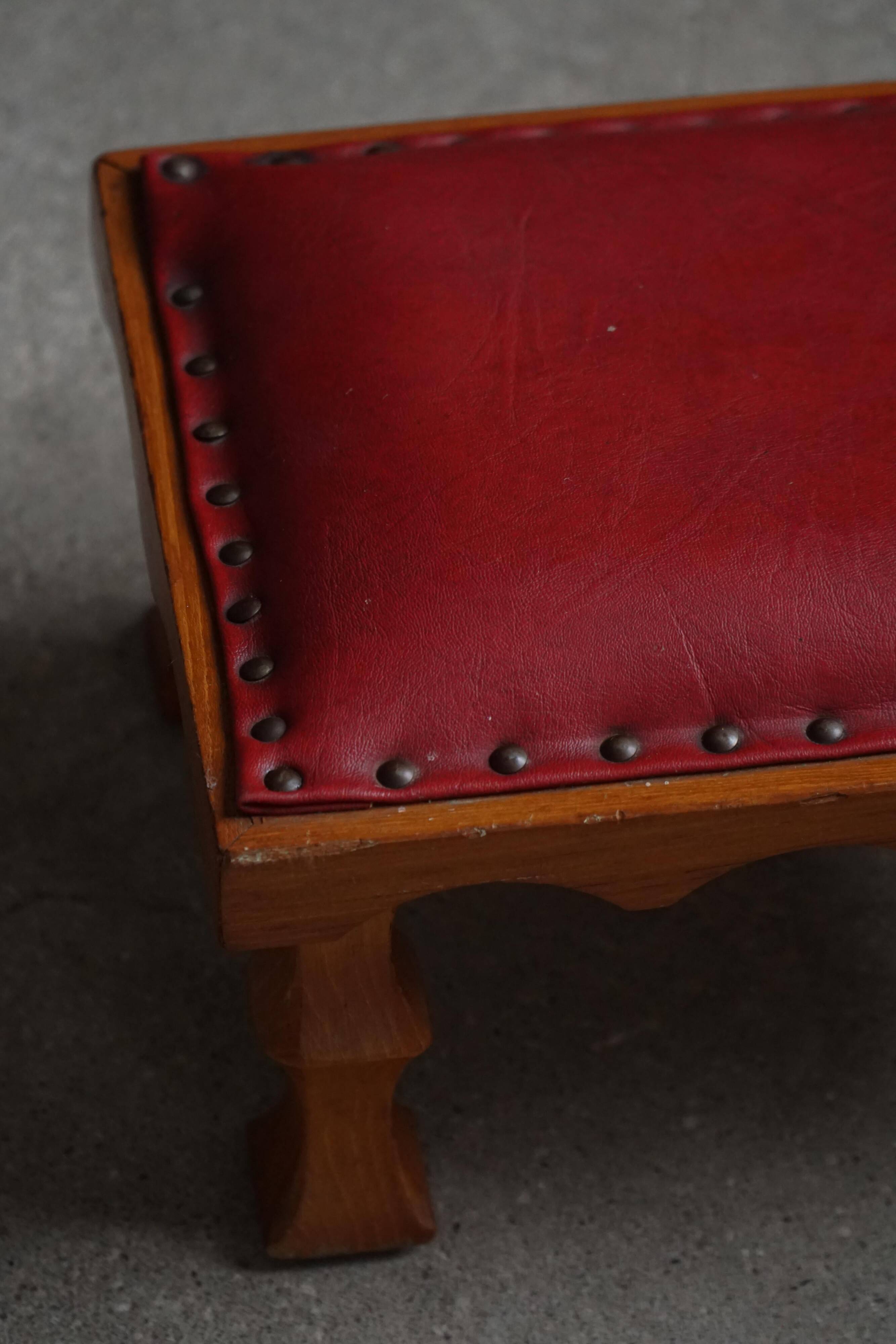 Danish sculpted oak stool from the mid-20th century with a red leather seat, 1950s.