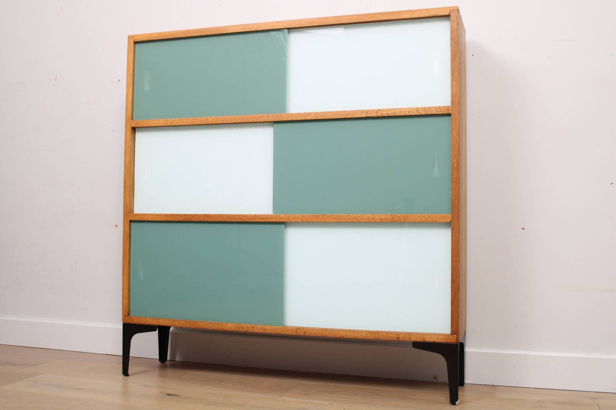 A vintage mid-century 3 tiered bookcase with glass sliding doors