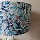 Table lamp with chrome stem, tropical plant shade.