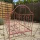 Old iron bed for children, painted pink with scrolls, romantic style.