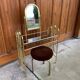 Hairdresser and vintage stool in gilded brass and mirror — brown seat, straw yellow accents.