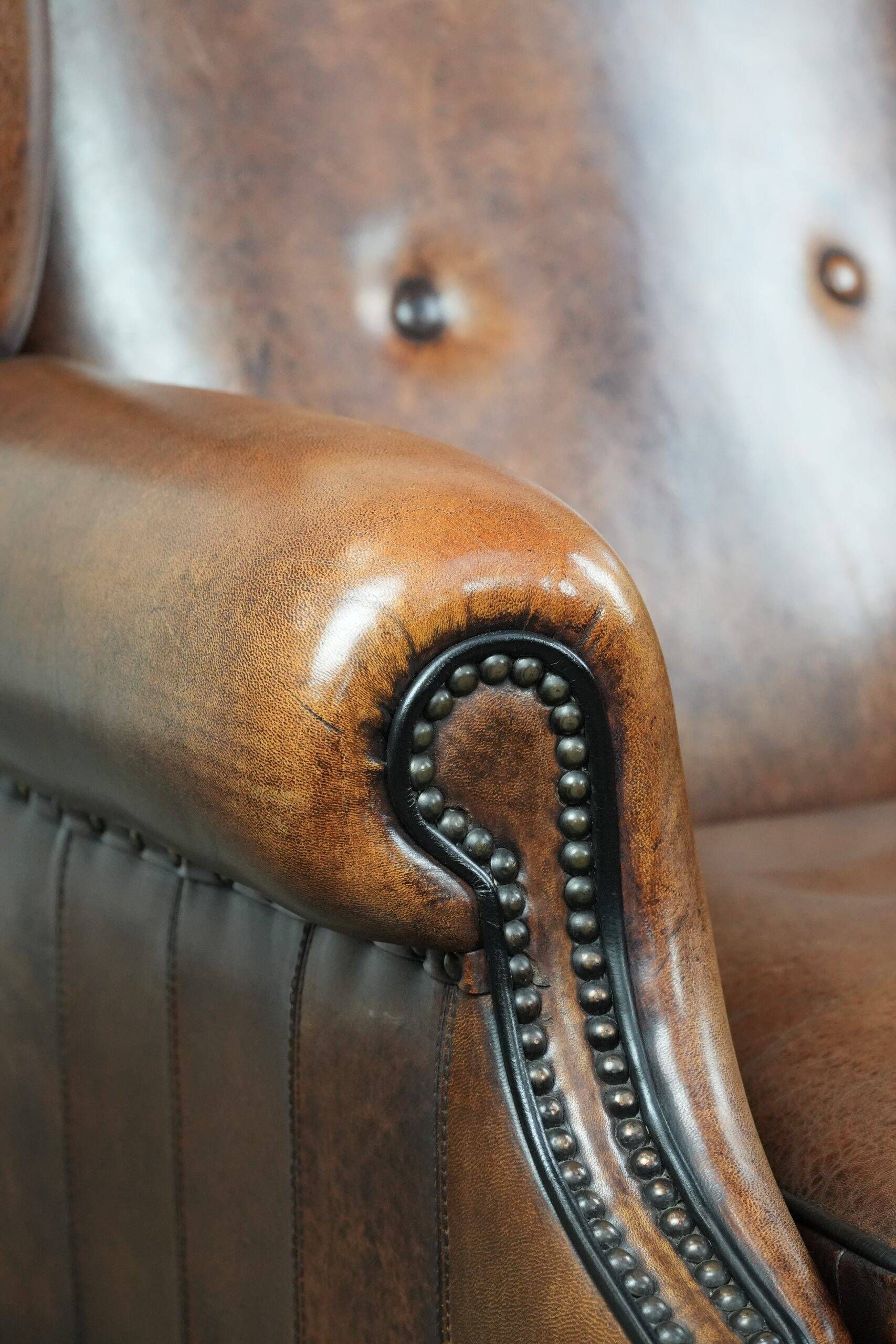 Sheepskin wingback armchair with decorative nails and black piping