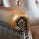 Sheepskin wingback armchair with decorative nails and black piping