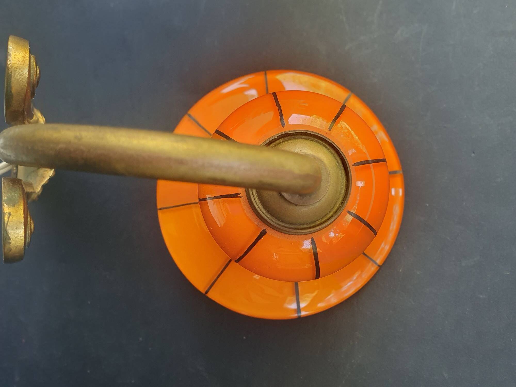 Art Deco wall light in brass with an orange globe.