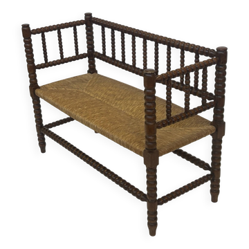 Banc vintage 'bobbin' avec assise en paille, design des années 1920 avec accoudoirs.