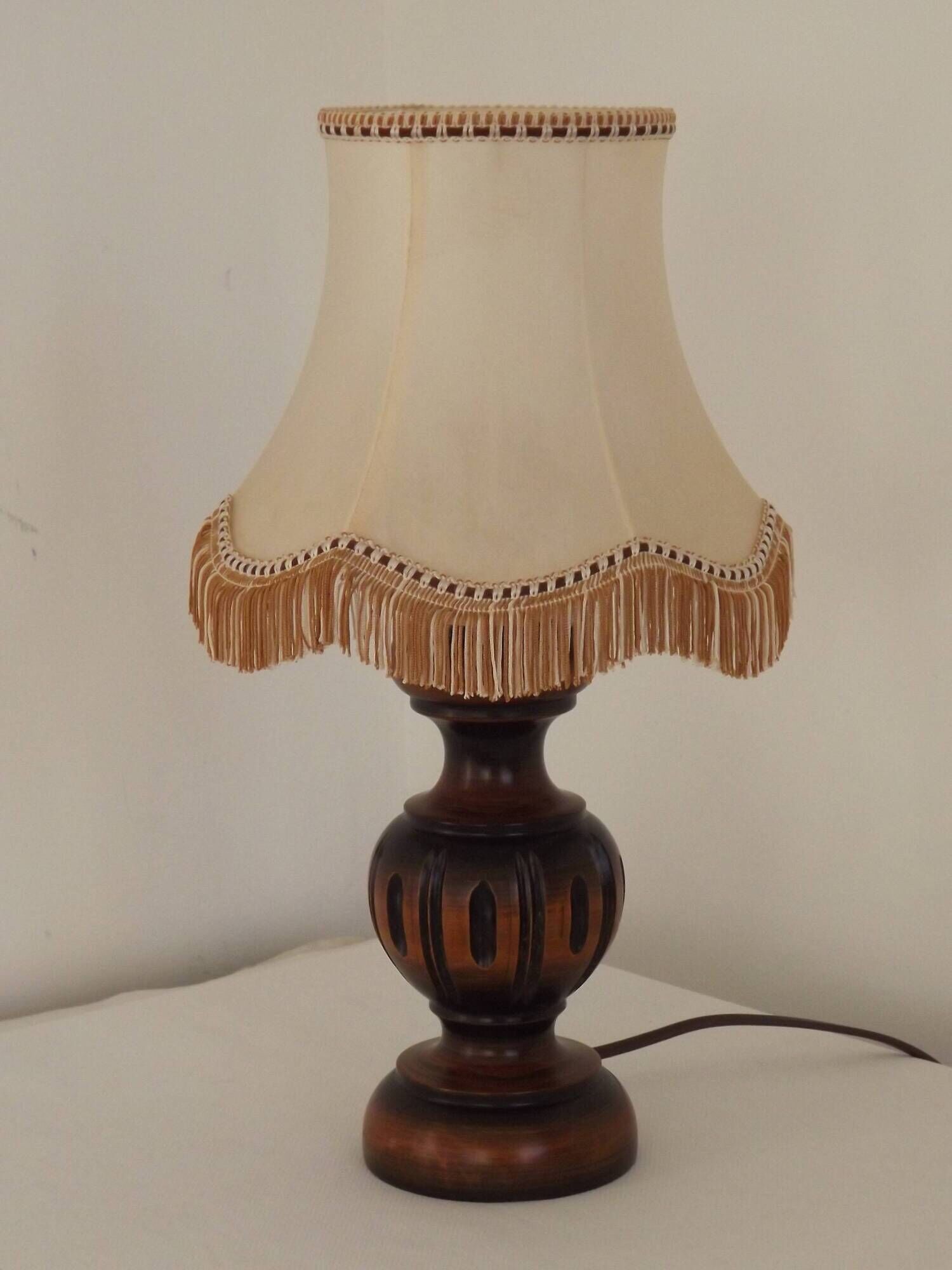 Mid-century French table lamp made of turned carved wood with a fringed shade.