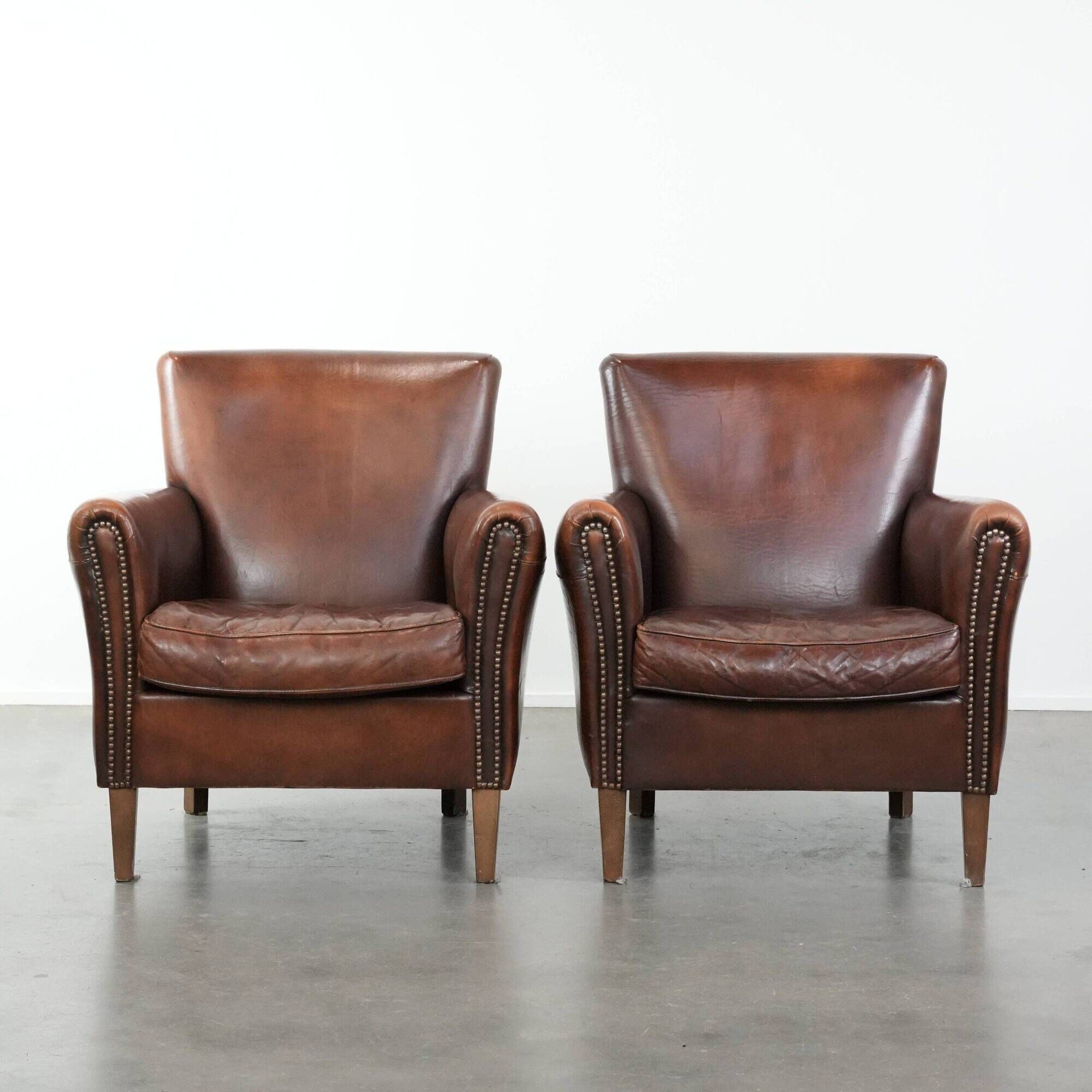 Ensemble de deux fauteuils en cuir de mouton vintage au caractère marqué.