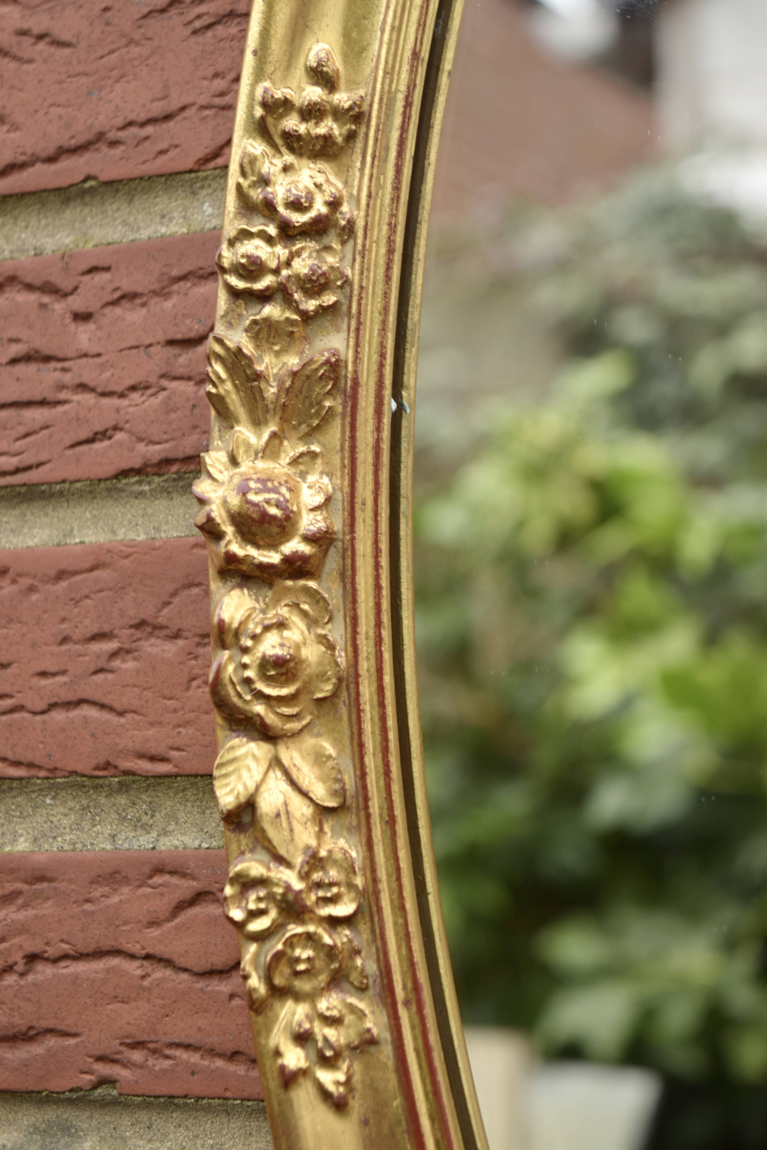 Old large oval wall mirror in golden resin