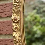 Old large oval wall mirror in golden resin