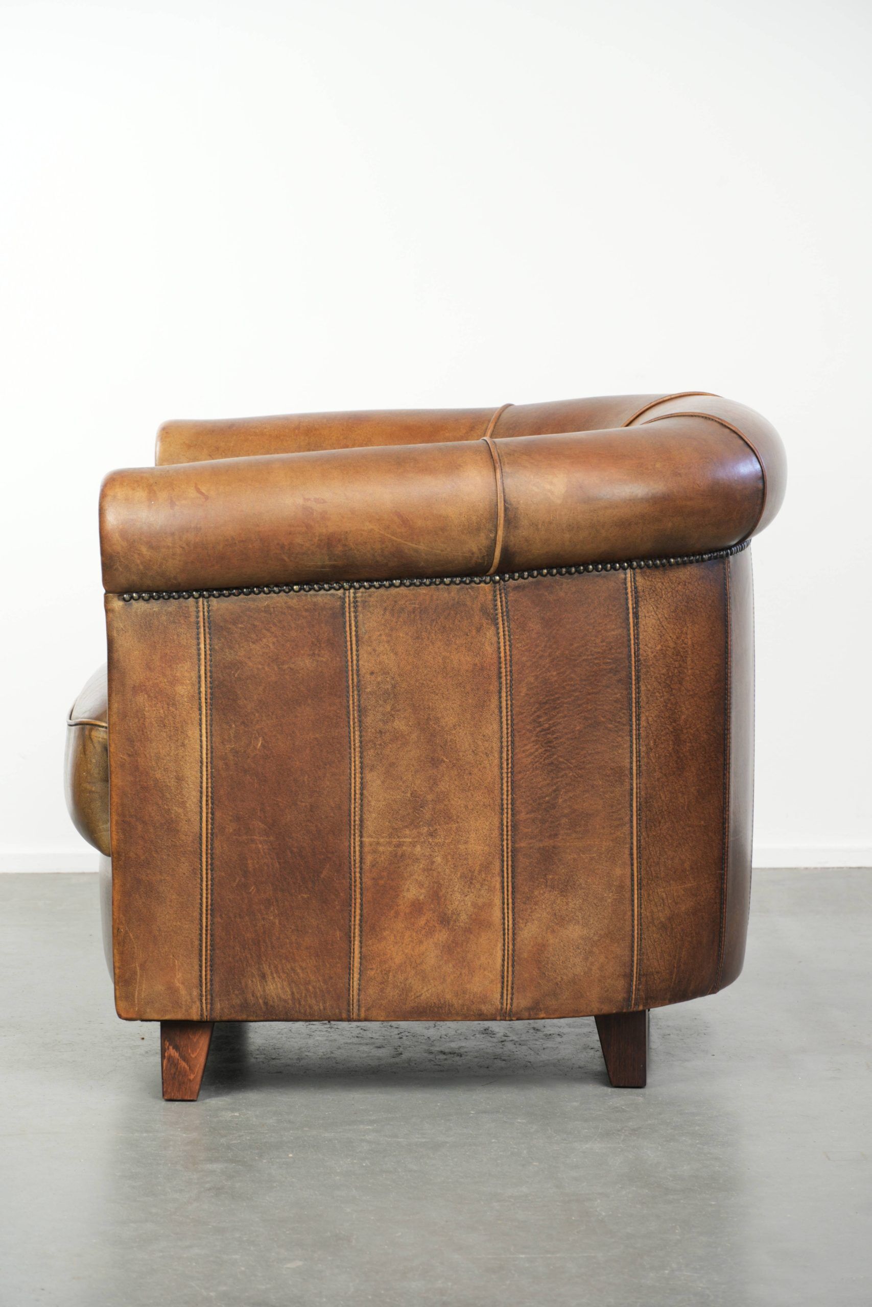 Sheepskin clubarmchair with beautiful patina finished with decorative nails