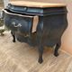 Curved commode painted in black and wood.