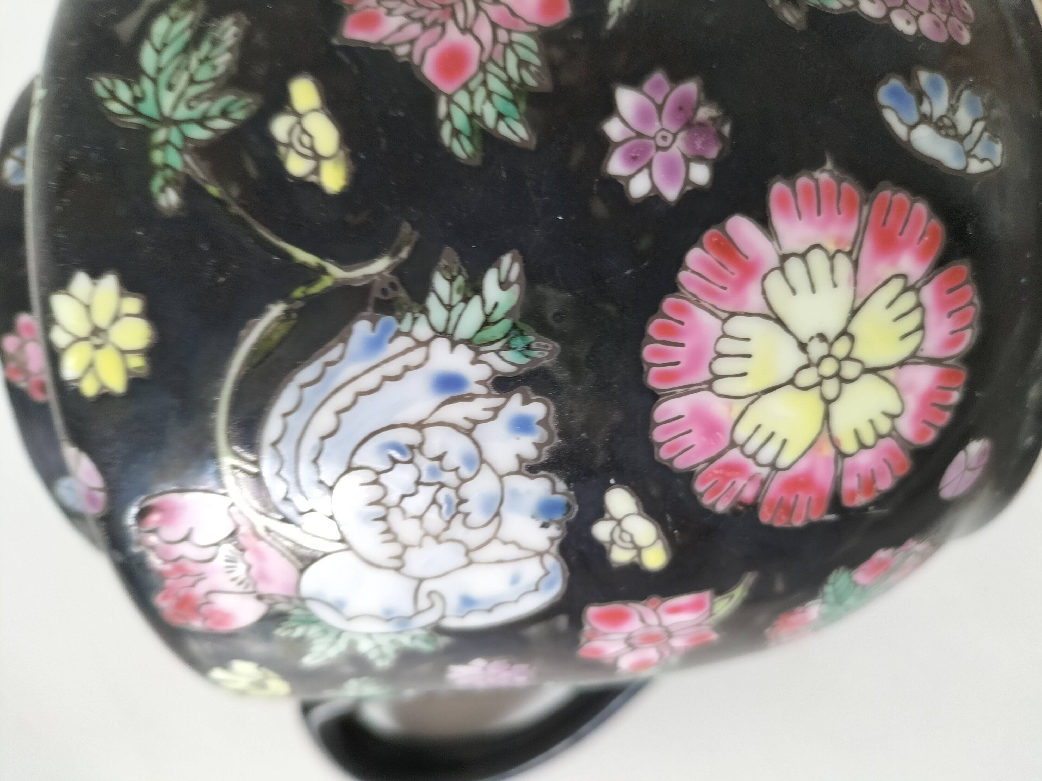 Vintage Chinese teapot with floral polychrome decoration on a black background.