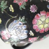 Vintage Chinese teapot with floral polychrome decoration on a black background.