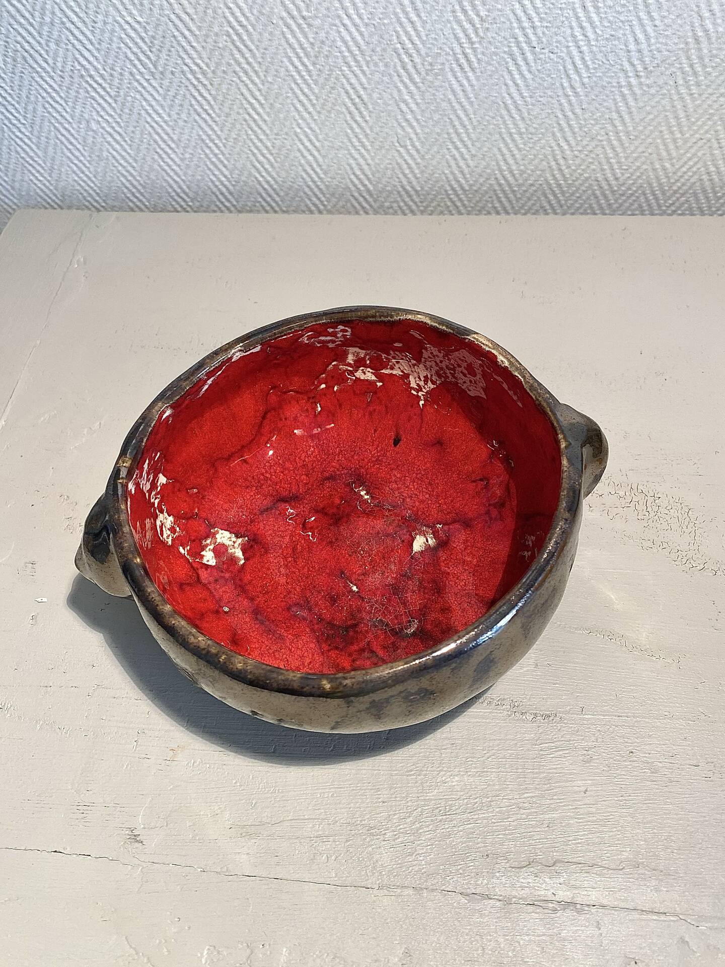 Deep red glazed and metallic ceramic catchall.