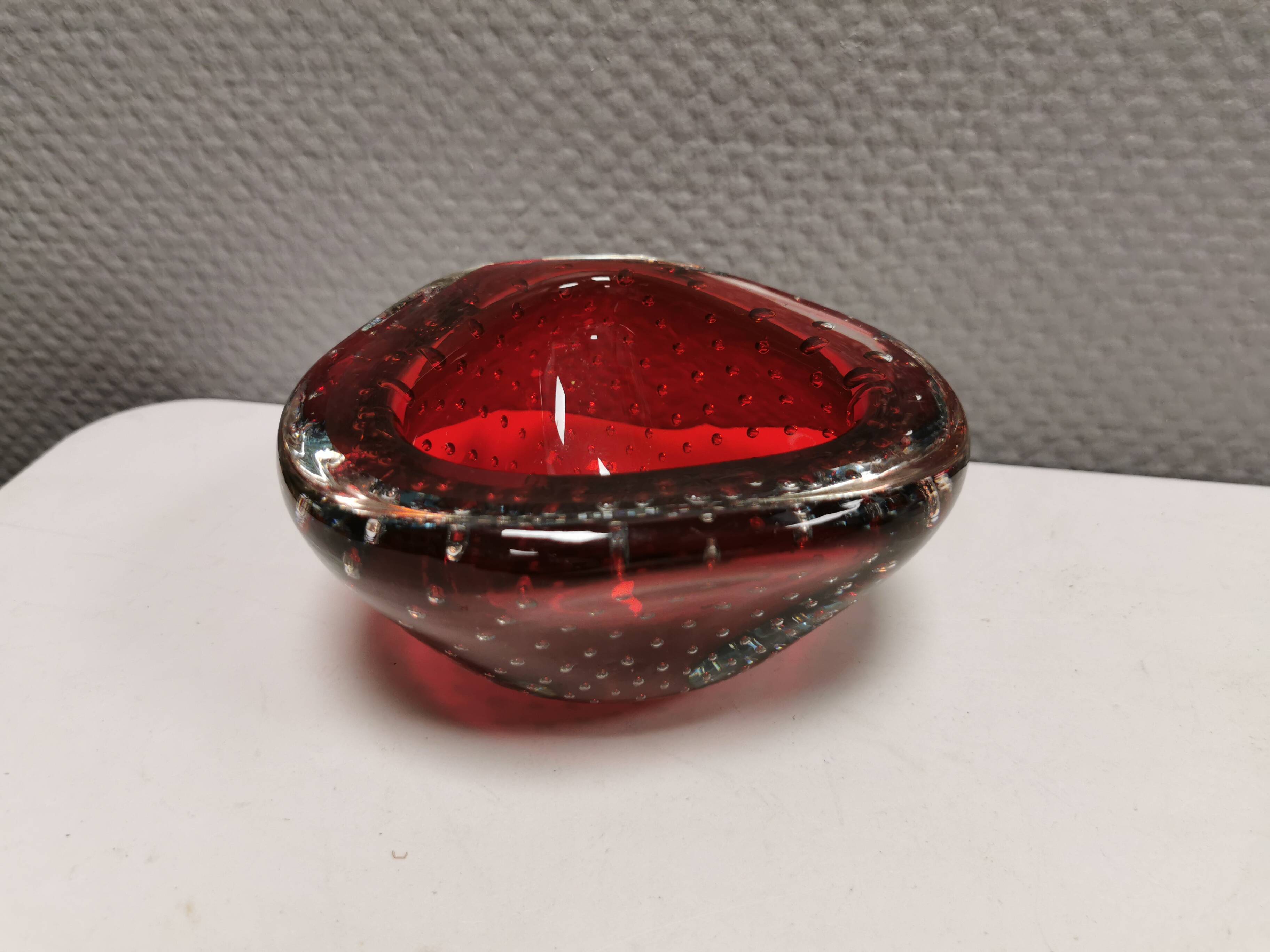 Small glass bowl in beautiful emerald red color with inlaid bubbles.