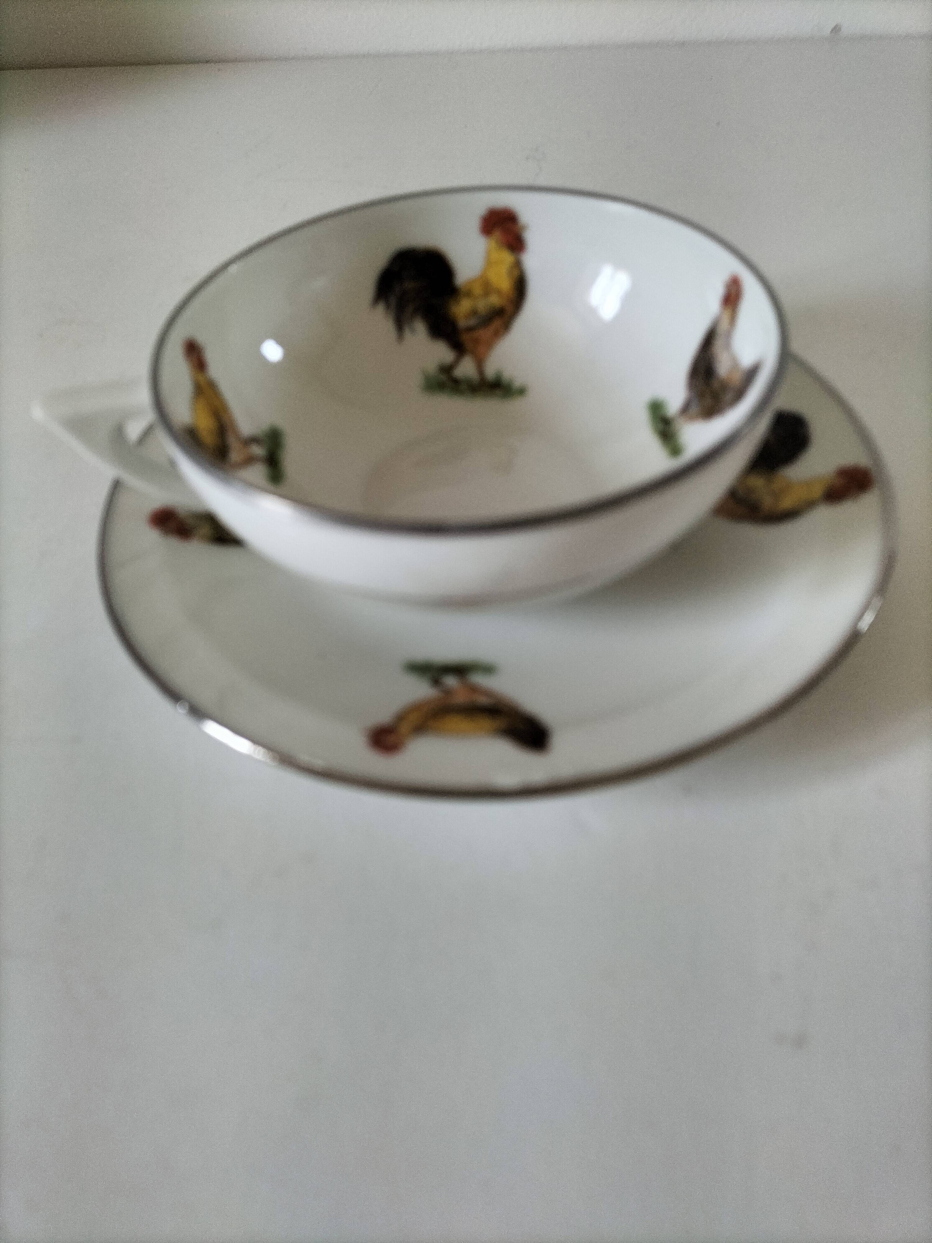 Cup and saucer in porcelain decorated with roosters and hens.