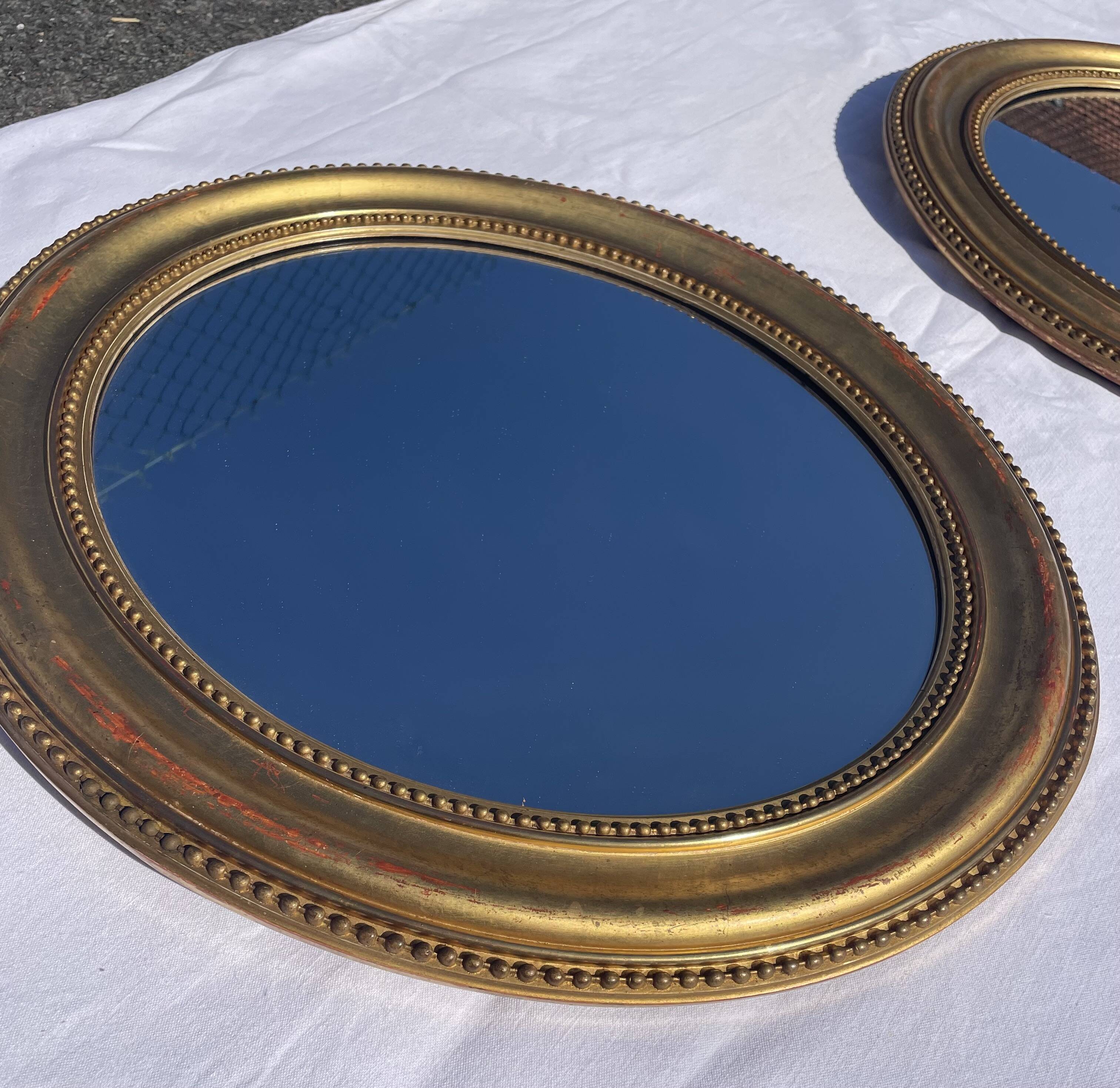 Duo de miroirs ovales et dorés en bois