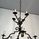 Two-tiered wrought iron chandelier with eight light arms in Gothic style.