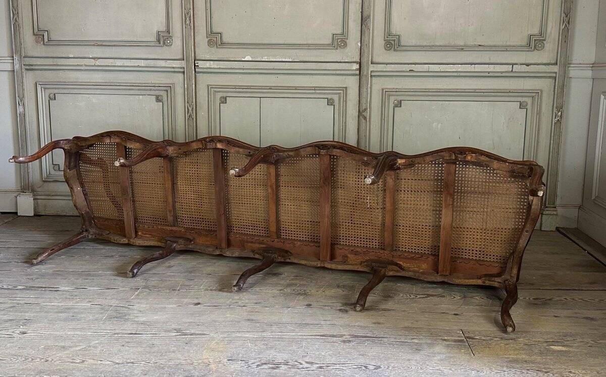 Grande banquette Louis XV en bois naturel mouluré et sculpté, France XVIIIème siècle