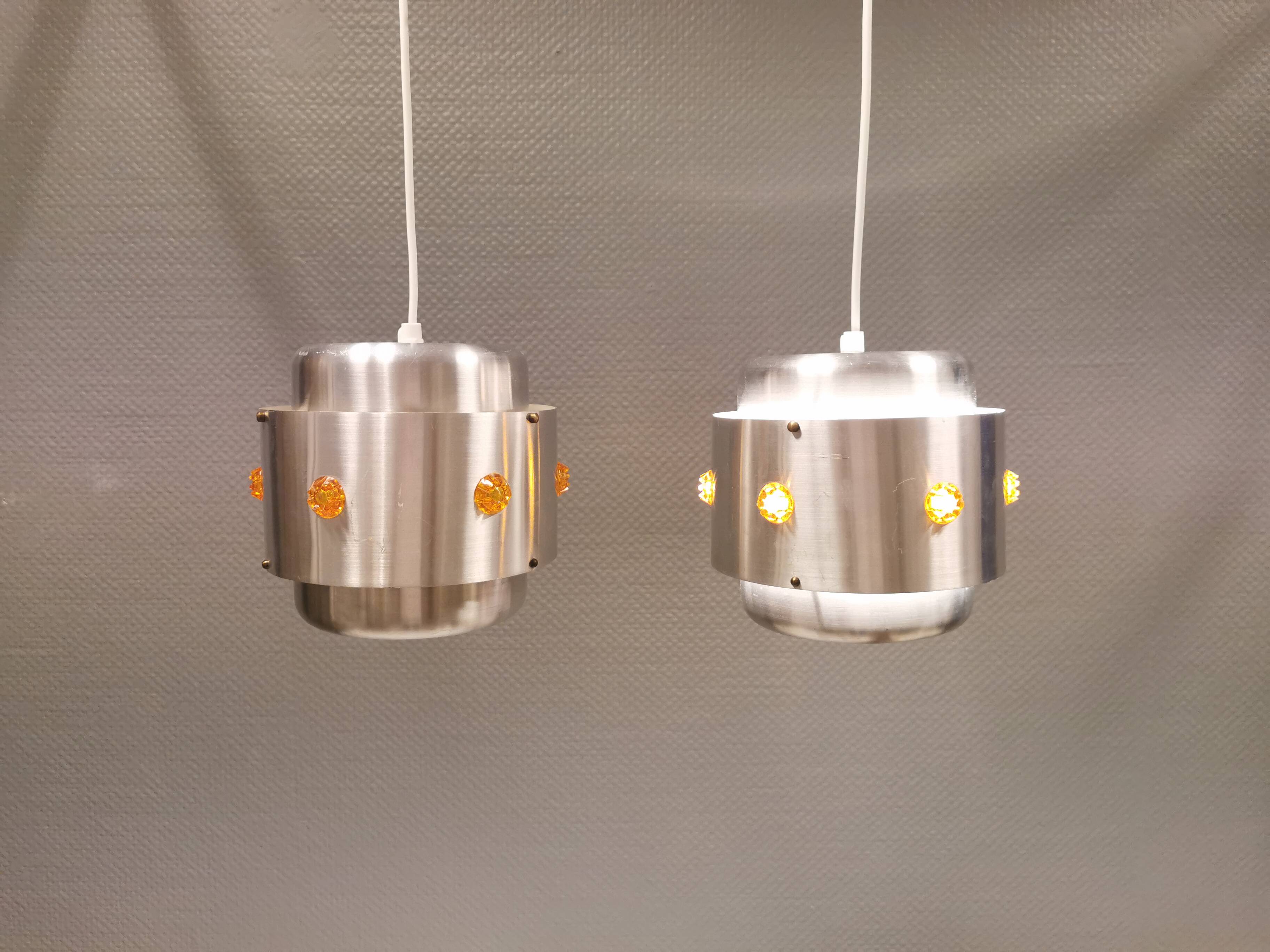 Two Space-Age hanging lamps, in silver-coloured aluminium with orange prisms.