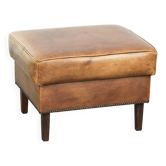Cowhide ottoman with a beautiful patina finished with decorative nails