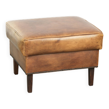 Cowhide ottoman with a beautiful patina finished with decorative nails