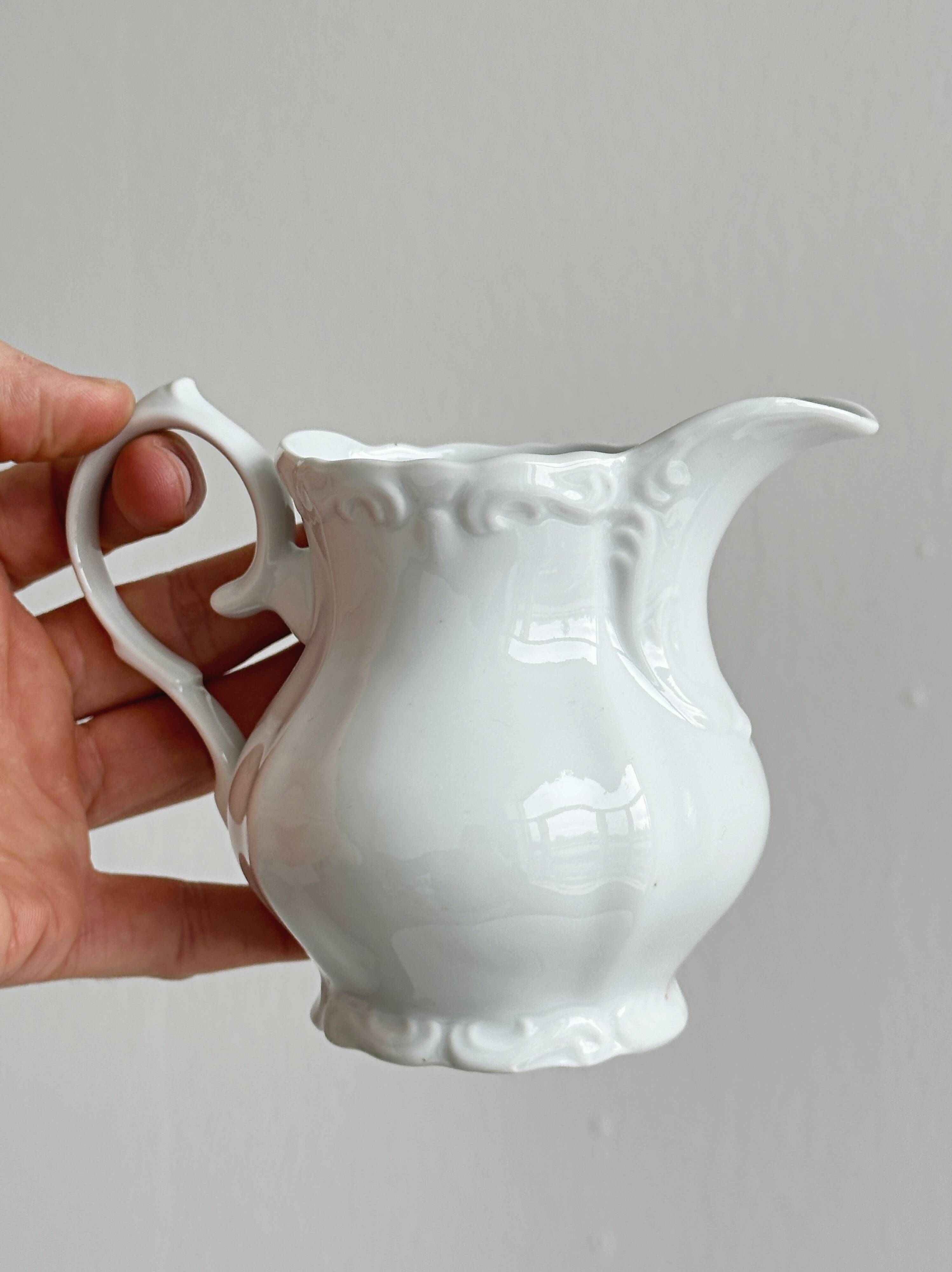 Old white porcelain milk jug, cream jug with relief.