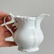 Old white porcelain milk jug, cream jug with relief.