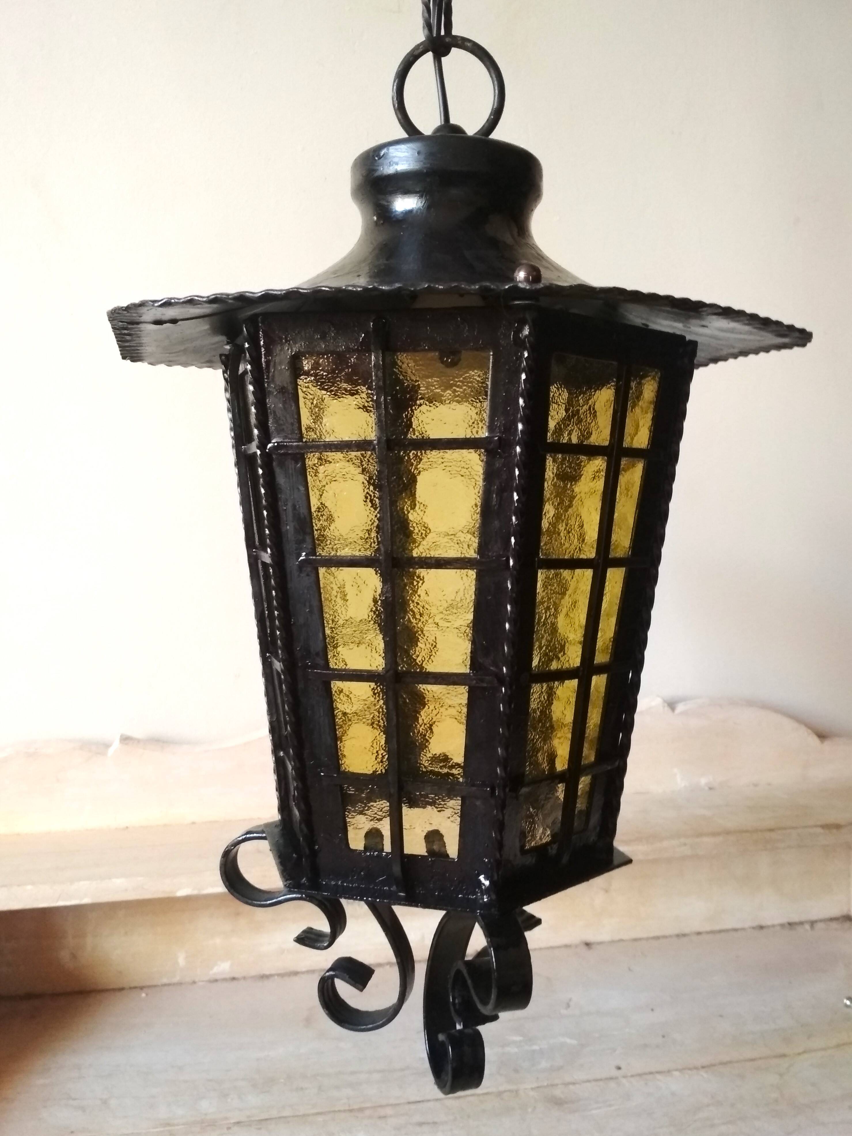 Large hanging lantern in wrought iron and opaque yellow-orange windows