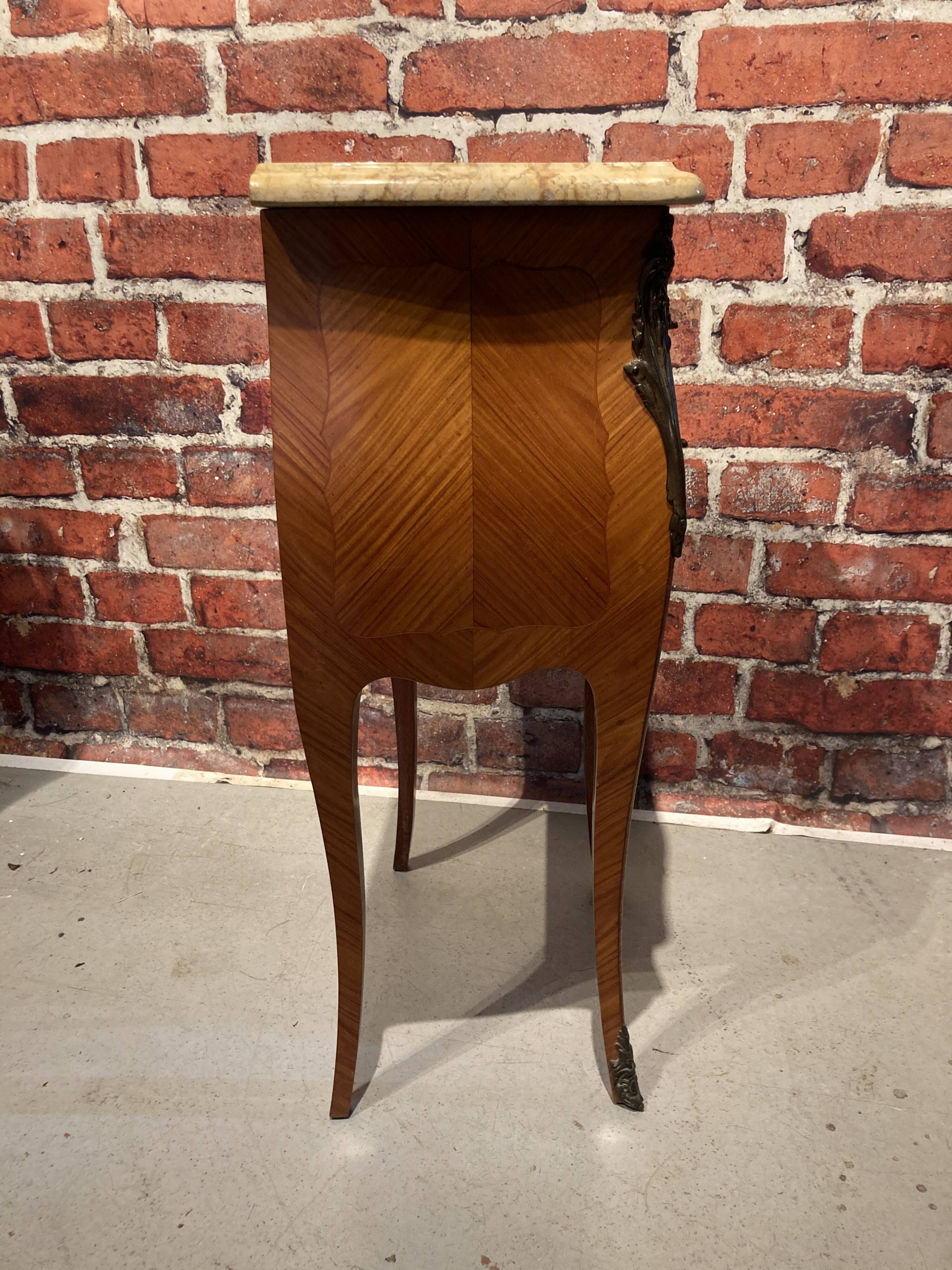 Wooden bedside table topped with a pink marble top