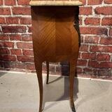 Wooden bedside table topped with a pink marble top