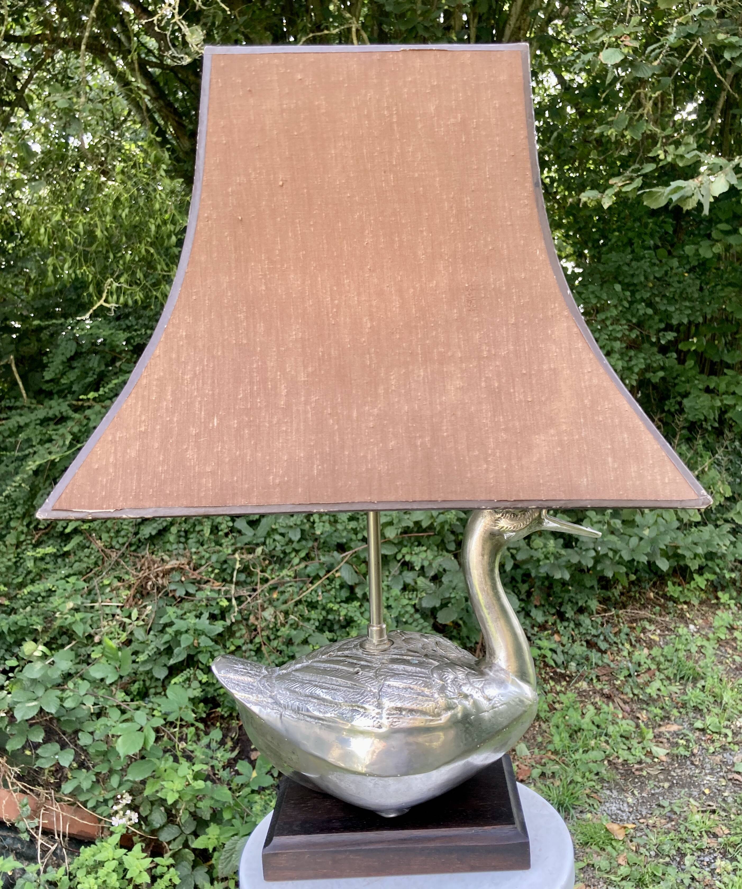 Old vintage lamp representing a duck in silver metal with wooden base