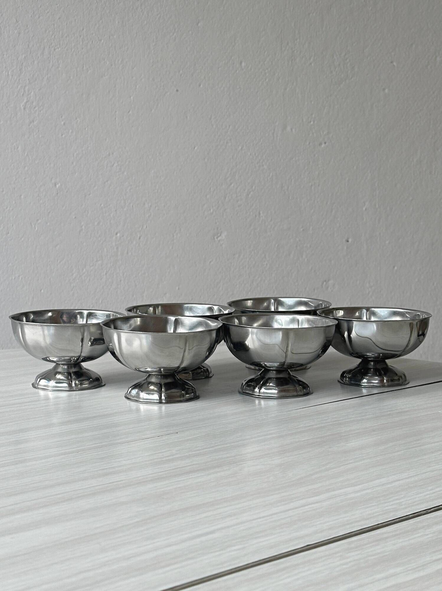 Set of 6 silver stainless steel ice cream bowls on a stand.