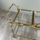 Rolling table cart in gilded brass with two glass shelves, 20th century.