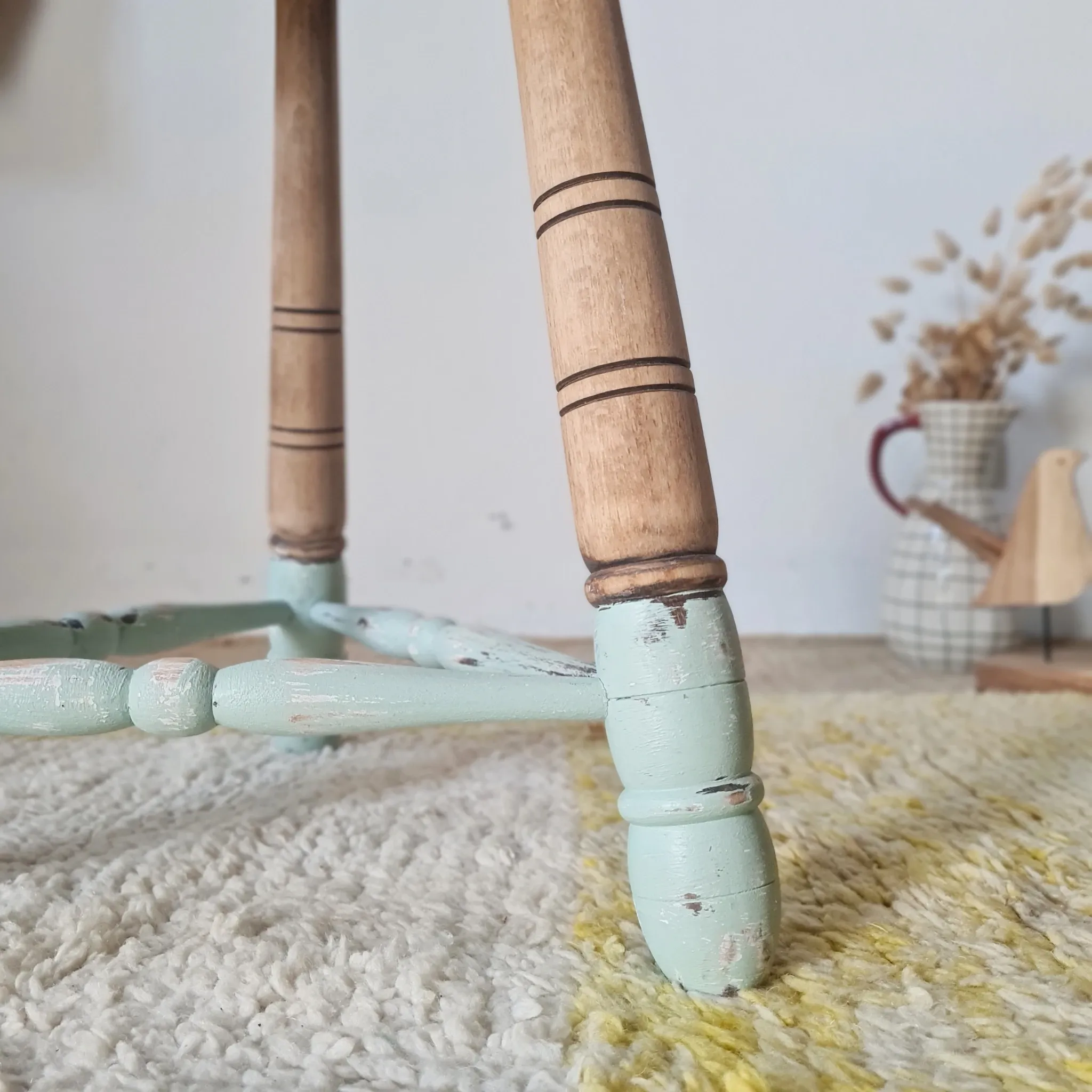 Antique tripod stool with blue striped seat.