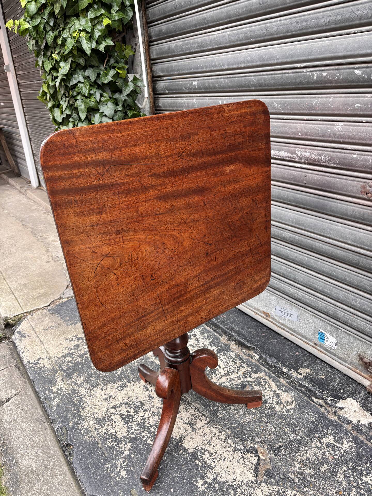 19th-century solid mahogany table with a tilting top and brass mechanism.
