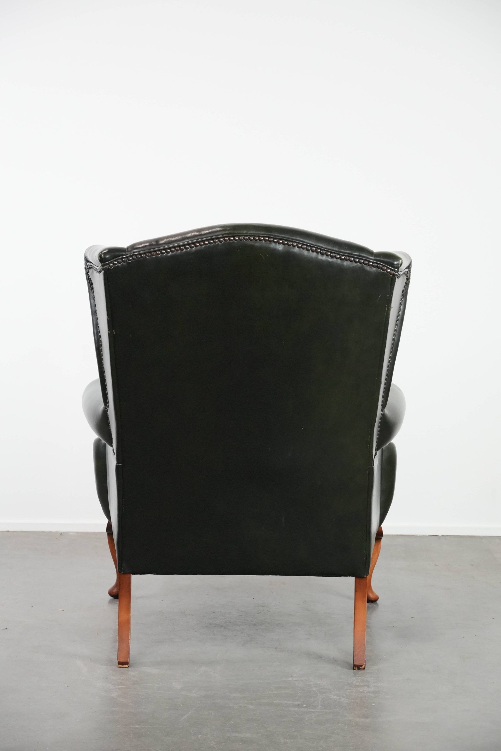 Smooth classic cowhide Chesterfield armchair in a stylish dark green color