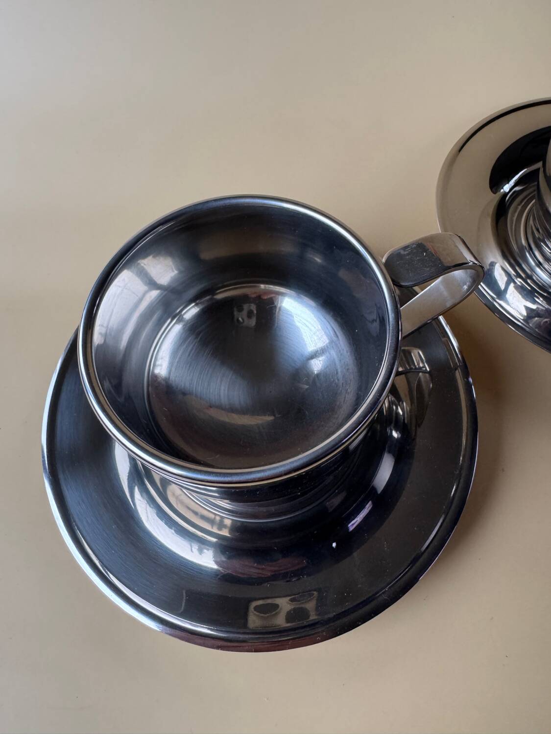 Two vintage mid century modern stainless steel coffee cups with saucer