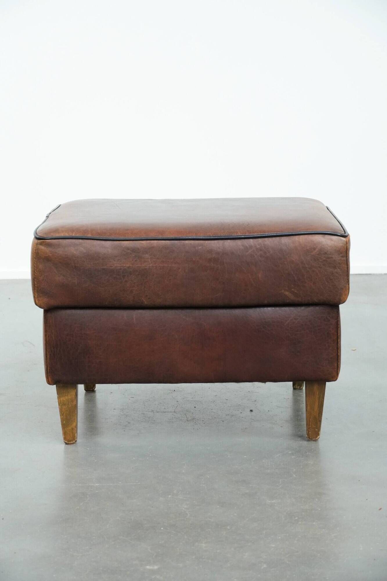 Sturdy vintage sheepskin ottoman in a beautiful large size with black piping