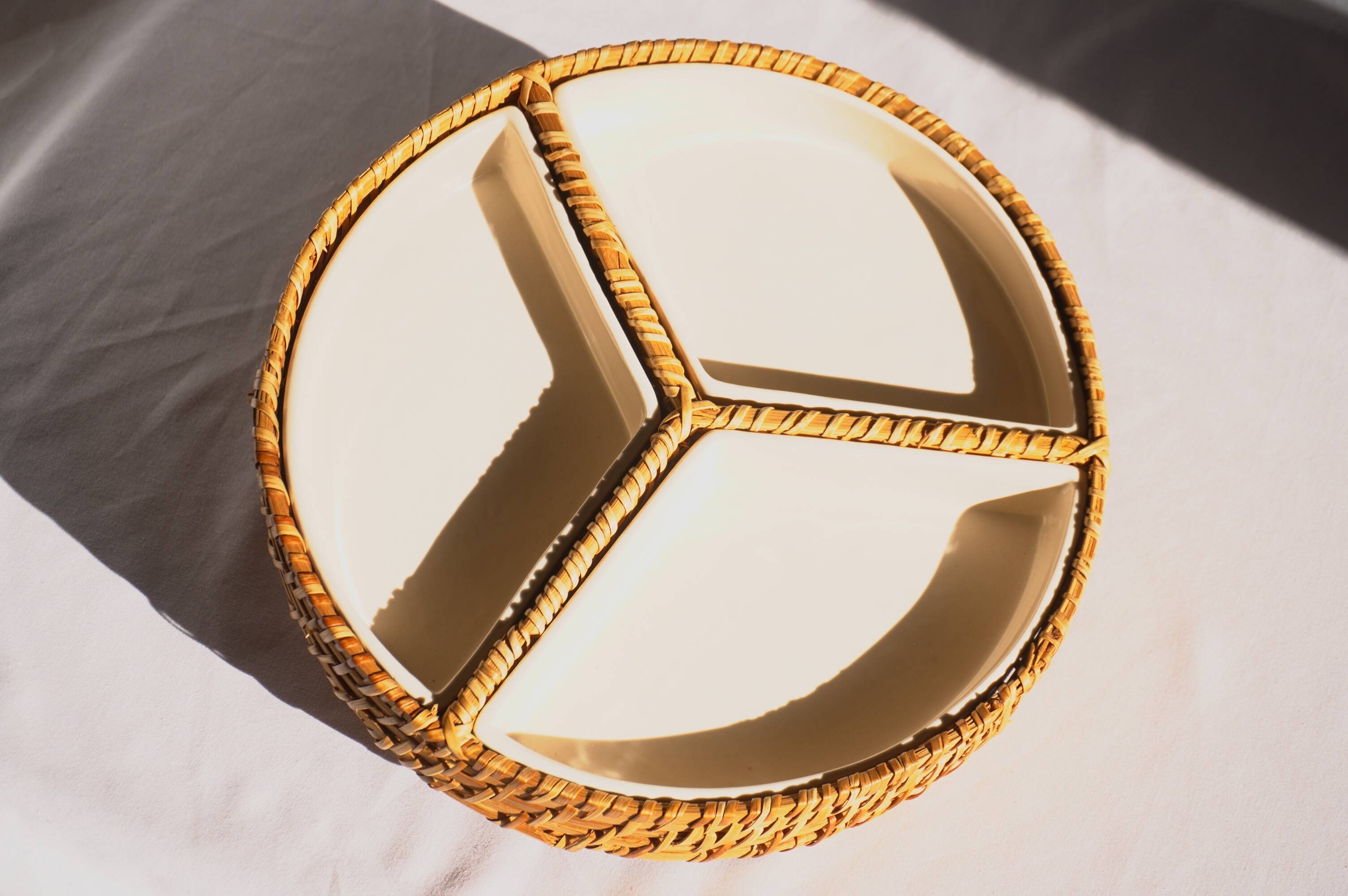 Compartment dish for appetizers, made of porcelain with a wicker support.