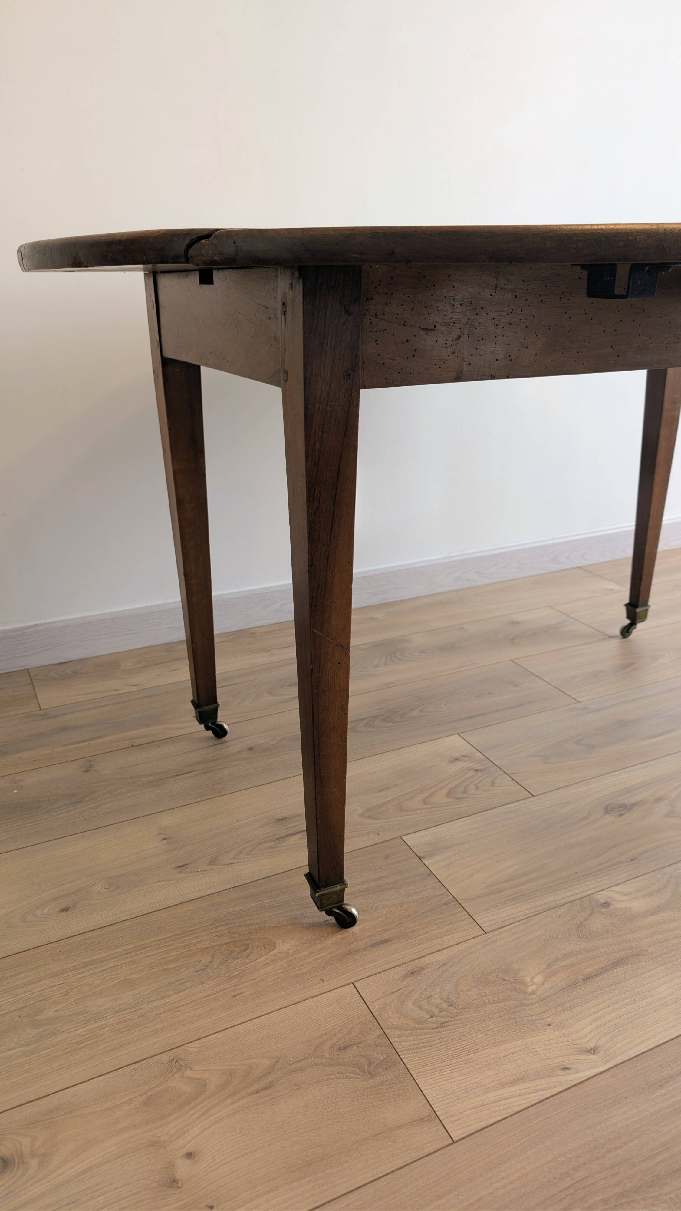 Antique wooden folding table with a patina and brass wheels.