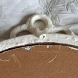 Round mirror in carved wood with at the top a ribbon forming a knot in cream color