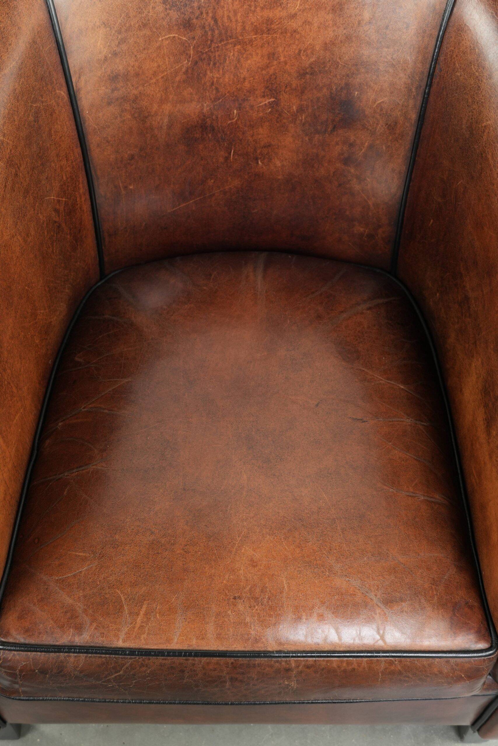 Sheepskin club armchair with deep warm colours and black piping