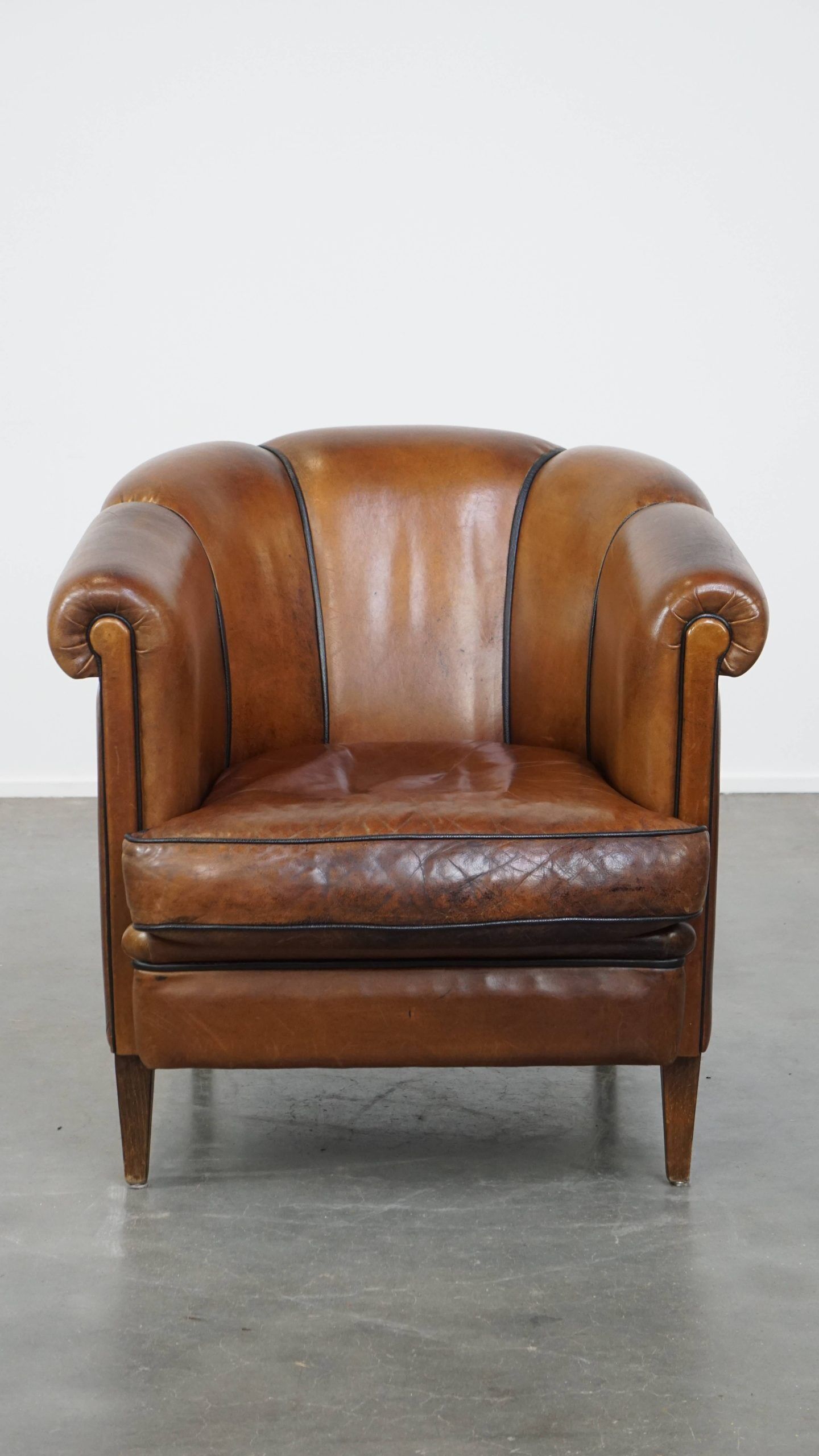 Unique vintage cognac-coloured leather club armchair with black piping