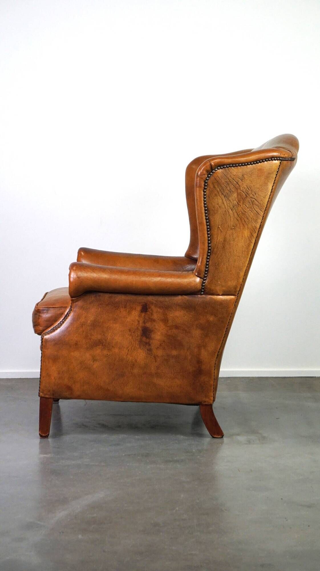 Positively lived-in sheepskin leather wing chair with pleasant seating comfort